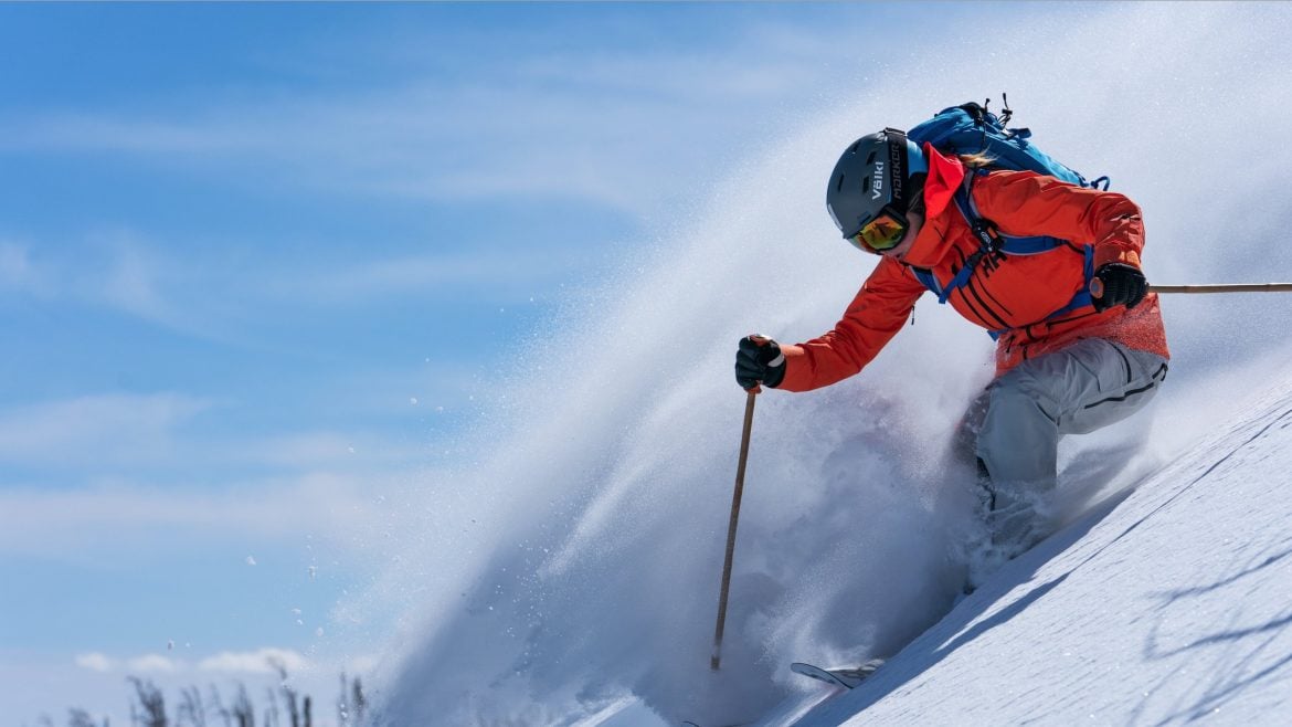 helly hansen man skiing down mountain in extreme weather snow