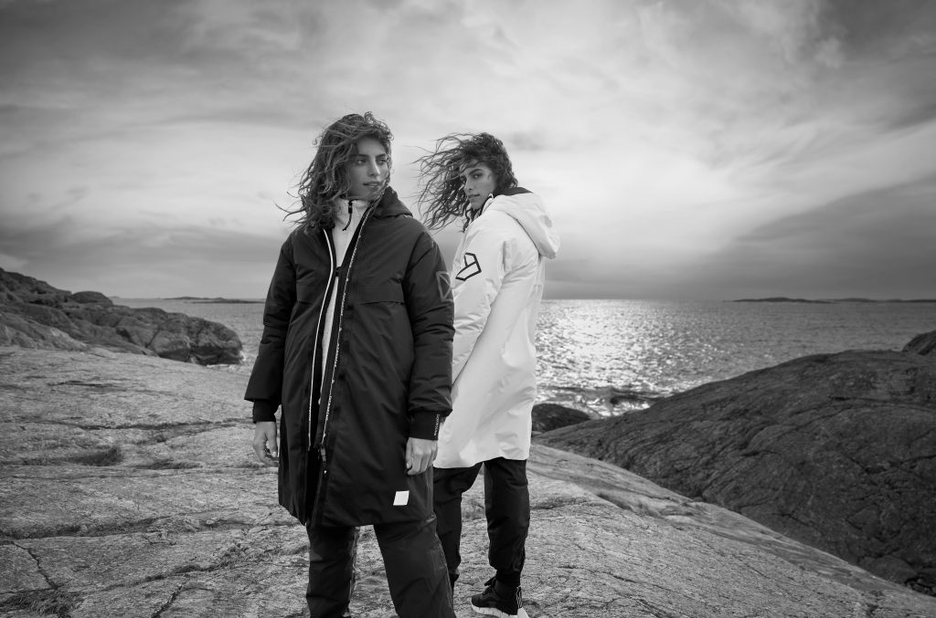 Two women wearing Didriksons Aino Parka stood by the sea